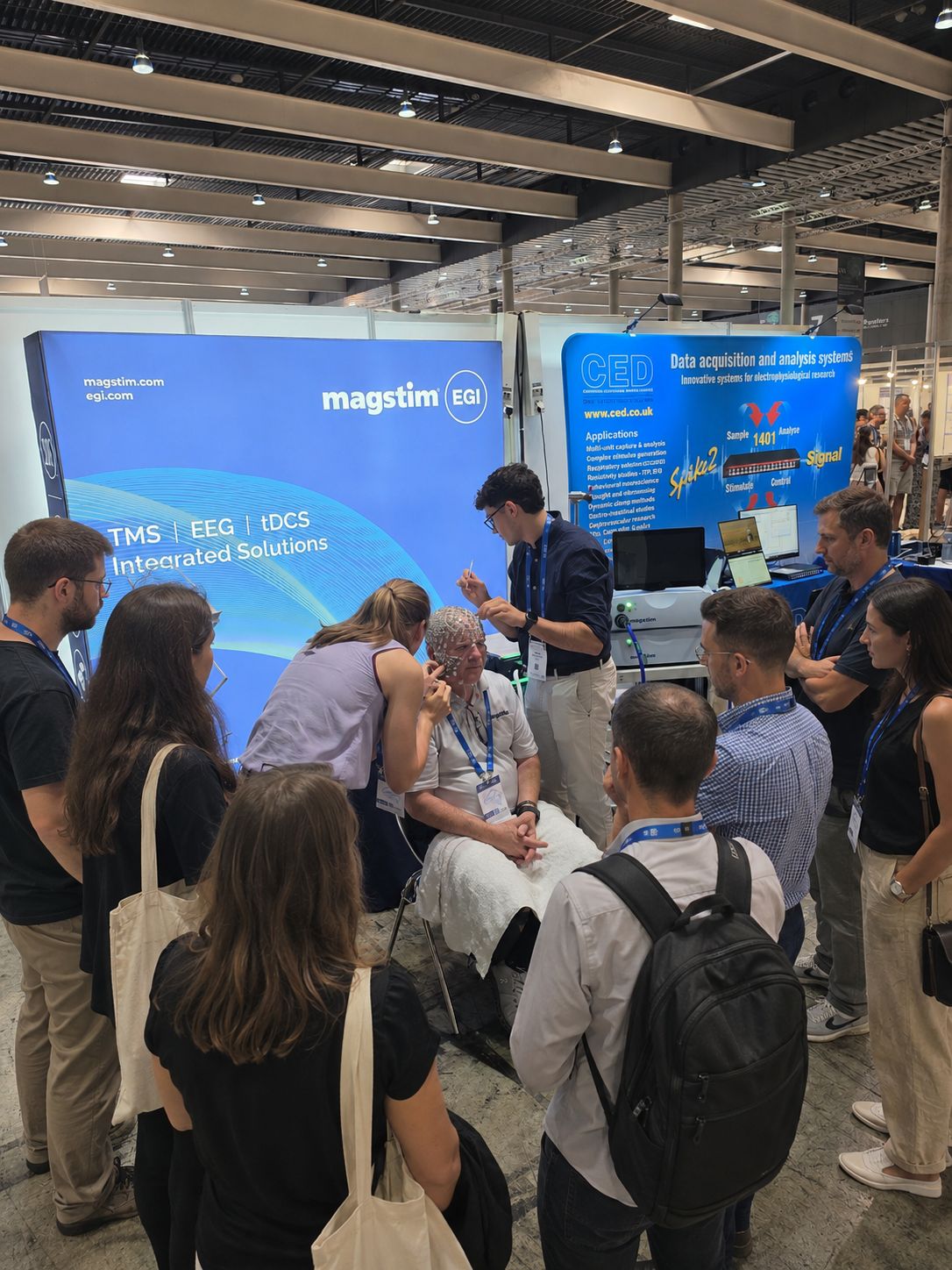 Participants réunis autour d’une démonstration EEG sur le stand Magstim EGI à FENS 2026